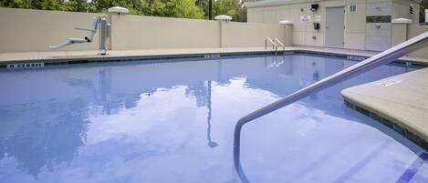 A swimming pool with a lifeguard chair, a changing room, and a covered area.