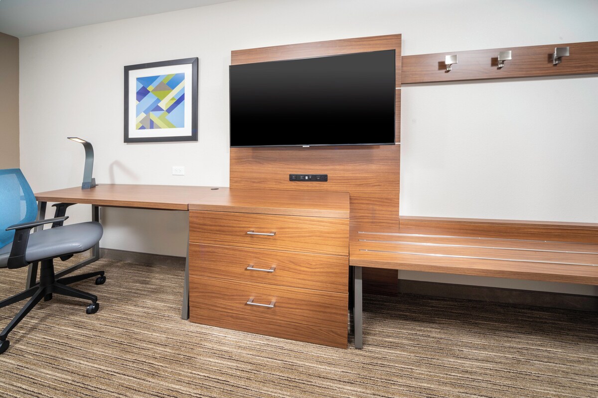 Een modern bureau met een flatscreen televisie, een houten tafelblad en een stoel.