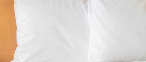 Una cama con ropa de cama blanca y cabecera de madera.