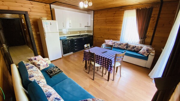A cozy cabin interior with a sofa, a dining table, and a kitchen area. - Kaya Residence Uzungol (Çaykara)