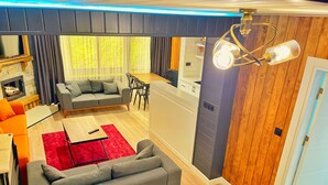 A modern living room with a grey sofa, red rug, and wooden flooring.