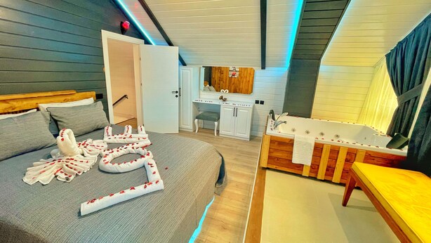 A modern bedroom with a bed, a vanity with a mirror, and a bathtub.