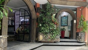 Entrada de hotel con arcos de piedra, plantas en macetas y un letrero que indica renovación.