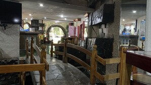 Un restaurante con suelo de piedra, mobiliario de madera y una pared de piedra.