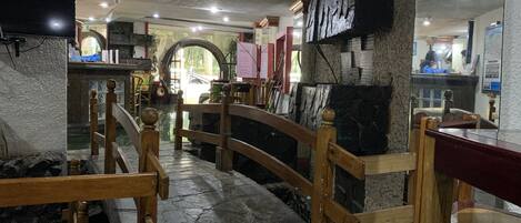 Un restaurante con suelo de piedra, mobiliario de madera y una pared de piedra.