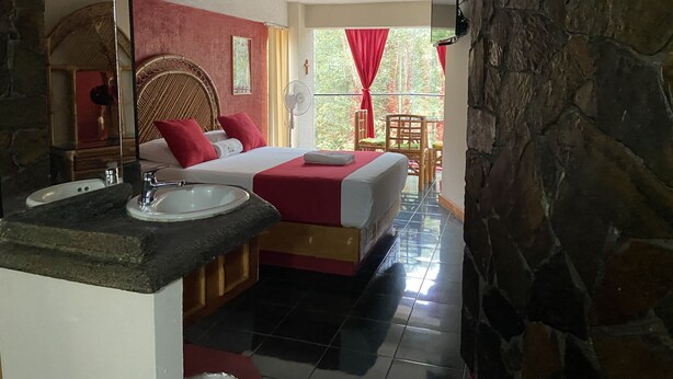 Habitación de hotel con cama, baño con lavamanos y vistas al exterior.