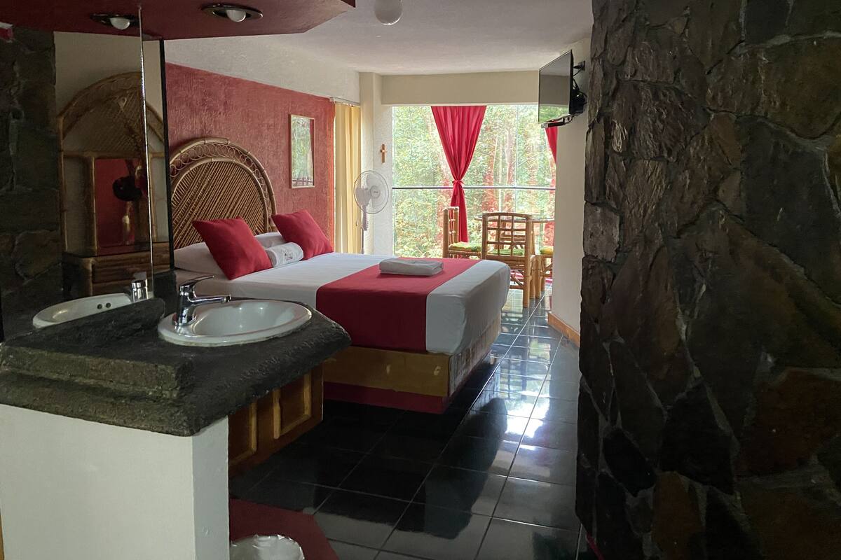 Habitación de hotel con cama, baño con lavamanos y vistas al exterior.