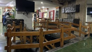 Un vestíbulo con pared de piedra, bancos de madera, un televisor de pantalla plana montado en la pared y suelo de baldosas.