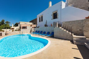 A swimming pool with blue water, surrounded by stone steps and blue lounge chairs. - Penthe Manor House, Rustic Secret Retreat (Koumi, Rethymno)