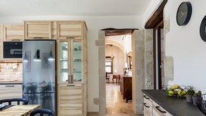 Une cuisine équipée d’un réfrigérateur en acier inoxydable, de meubles de rangement en bois et d’un coin repas avec une table et des chaises.