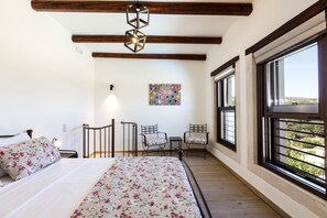 A bedroom with a bed, two chairs, a small table, a hanging light fixture, and large windows with a view. - Penthe Manor House, Rustic Secret Retreat (Koumi, Rethymno)