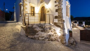 Un bâtiment blanc aux murs de pierre, doté d’une porte en bois et d’une rambarde en métal.