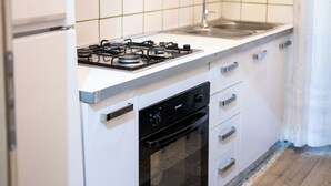 A kitchen with white cabinets, a gas stove, a sink, and a dishwasher. - Home Josèphine (Caserta)