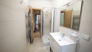 A modern bathroom with a shower, a sink, and a mirror. - Home Josèphine (Caserta)