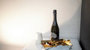 A bottle of wine, a white cup, and a box of chocolates on a white table. - Home Josèphine (Caserta)
