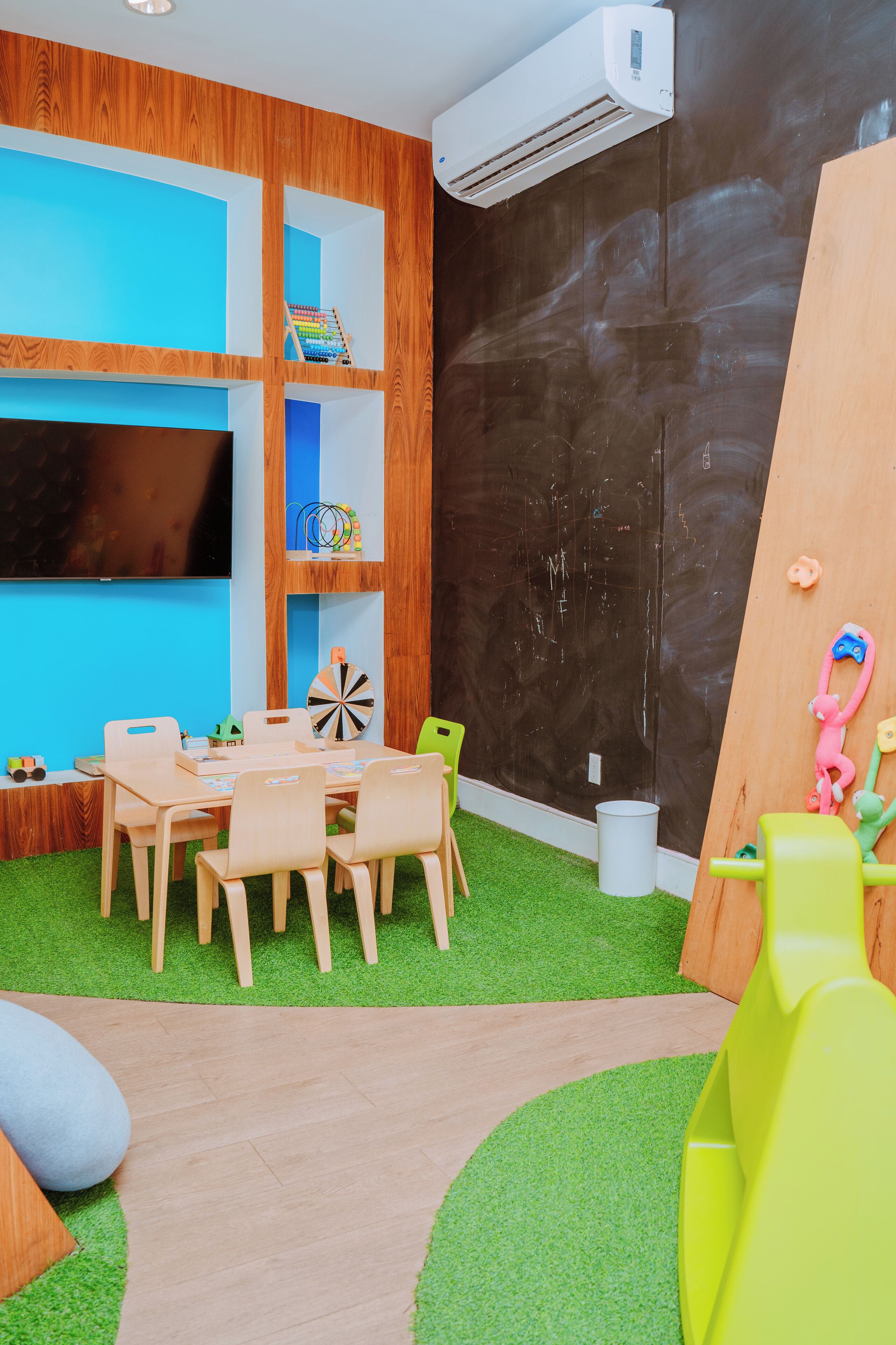 Een speelruimte voor kinderen met een tafel, stoelen en een klimmuur.