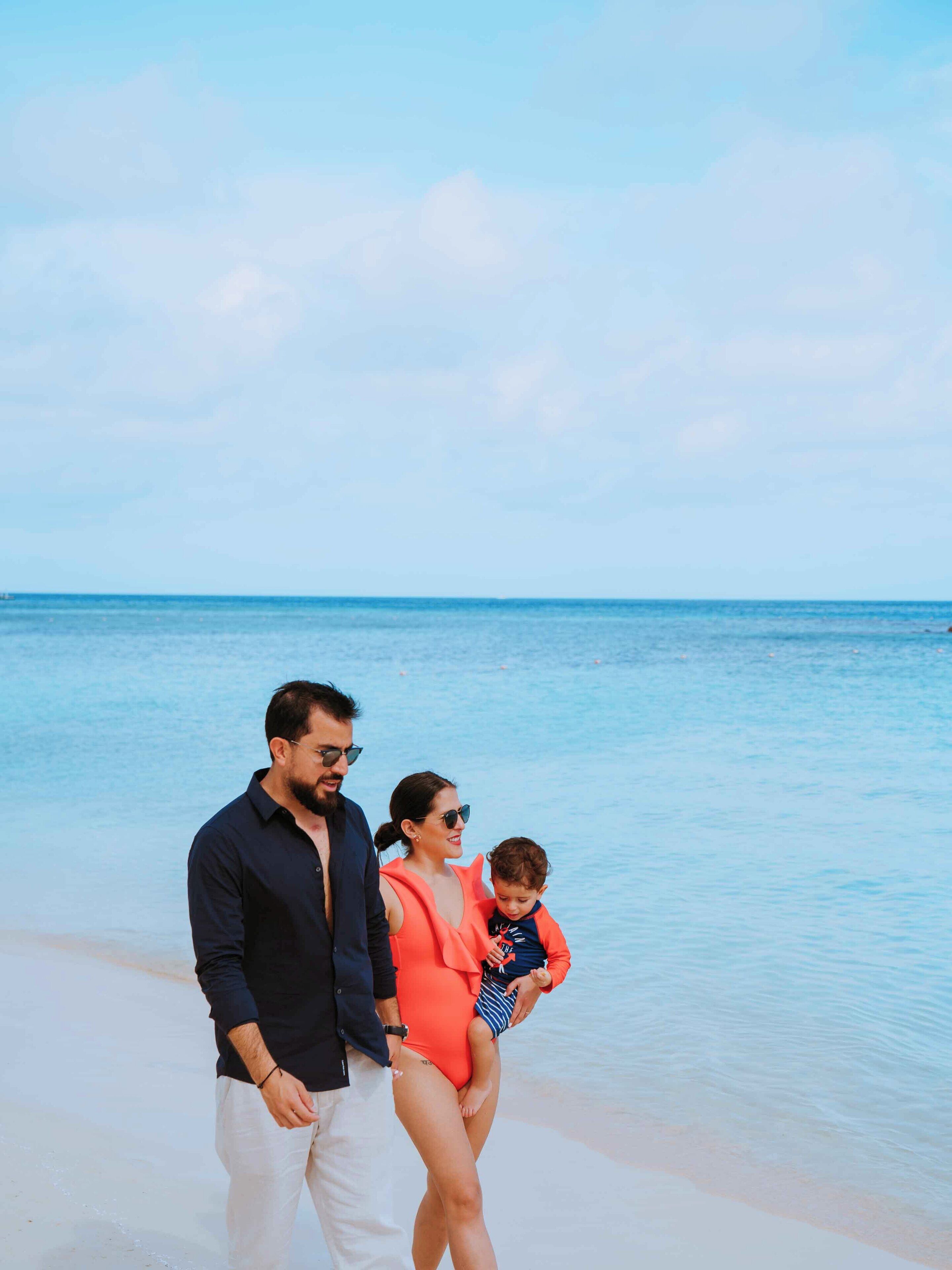 Una familia caminando en la playa bajo un cielo despejado.
