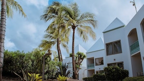 A modern building with a white facade, multiple balconies, and a paved walkway. - The Mill Resort & Suites (Noord)