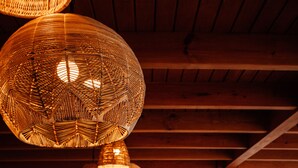 Un restaurante con lámparas colgantes de mimbre, mesas y sillas de madera.