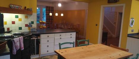Una cocina con una mesa y sillas de madera, estufa y microondas.