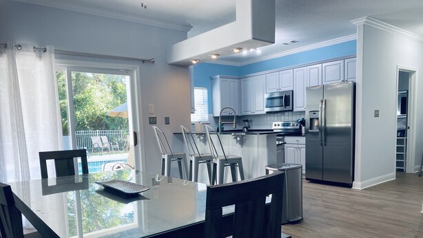 A modern kitchen with white cabinets, stainless steel appliances, and a glass dining table. - Private Pool, 6 passenger Golf Cart, and 4 bikes! EV charger on site! (Destin)