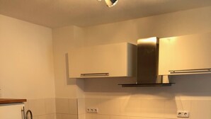 Una cocina moderna con armarios blancos, encimera de madera, horno empotrado y campana extractora de acero inoxidable.