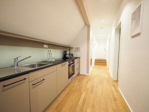 A modern kitchen with a stainless steel sink, a coffee maker, and a wooden floor. - Hotel Le Baldinger (Bamberg)