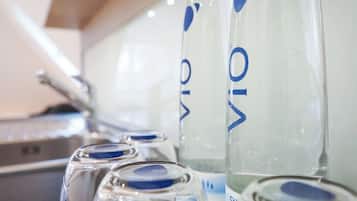 A row of clear glass bottles with blue labels, likely containing a beverage, arranged on a surface.