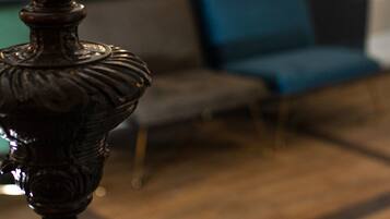 A close-up of a decorative object, possibly a lamp, with a blurred background featuring a blue sofa and a wooden floor.