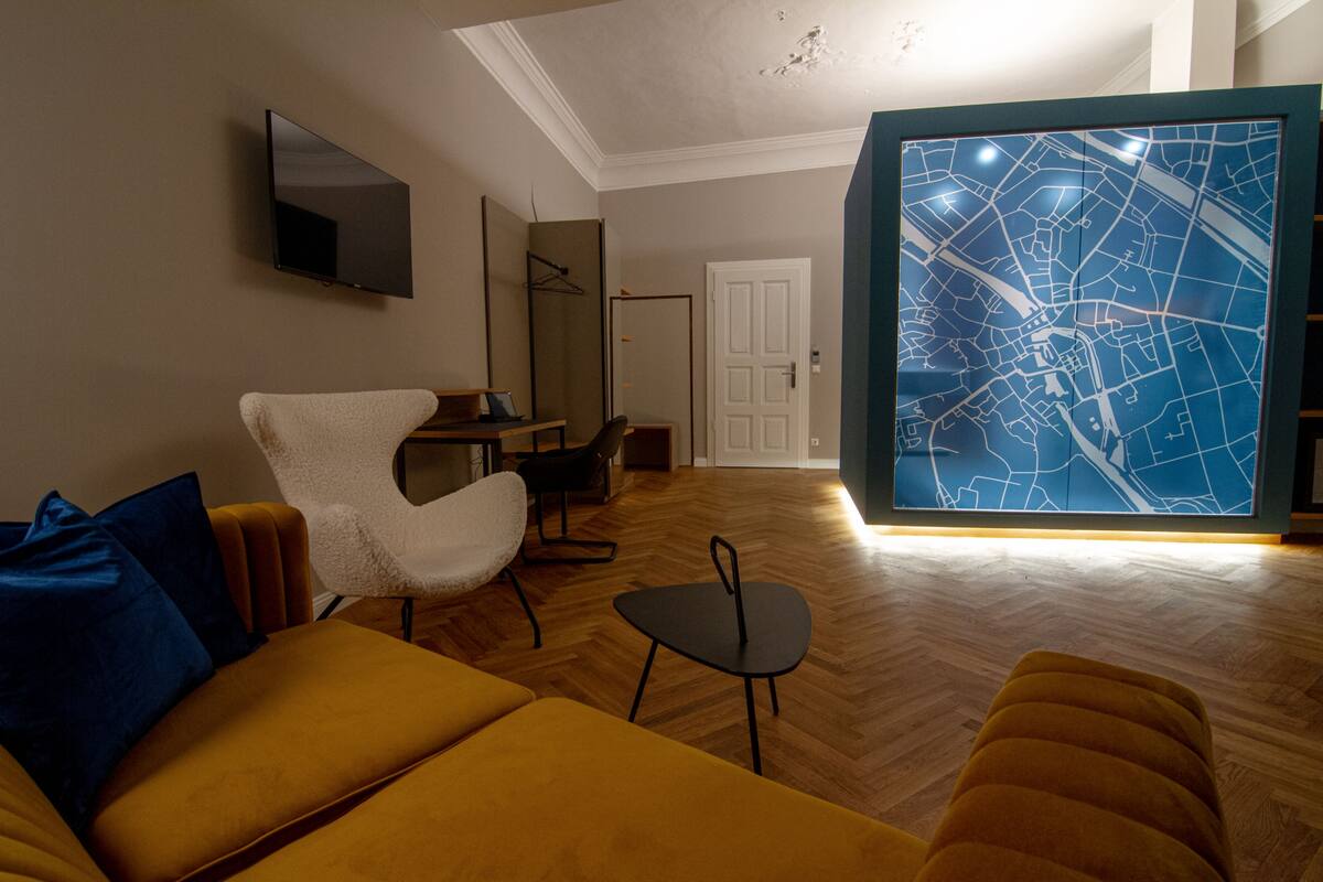 Una sala de estar moderna con un sofá, un sillón y una mesita. Un mapa grande está colgado en la pared.