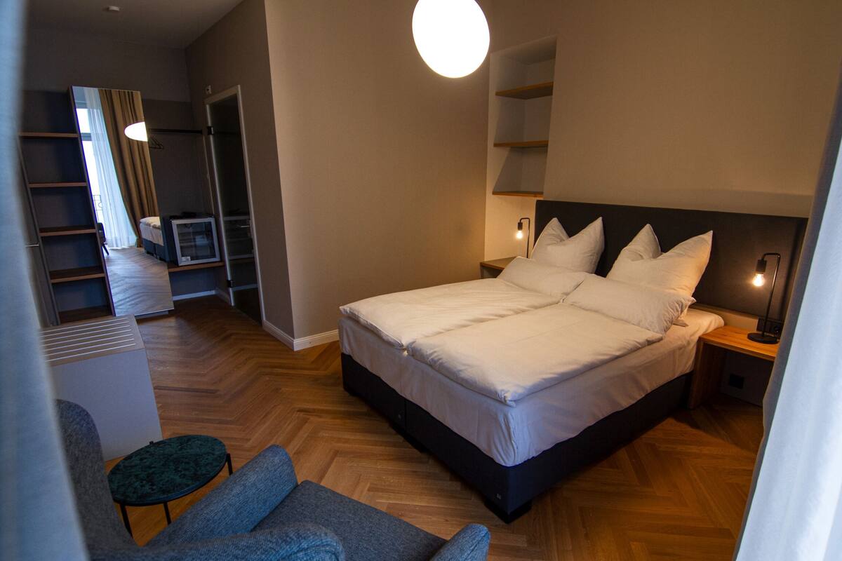 Una habitación de hotel moderna con una cama grande, una zona de estar pequeña y un vestidor.
