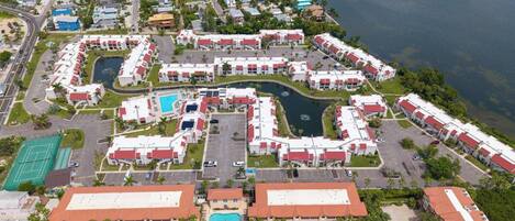 An aerial view of a resort with multiple buildings, a central pool, and a marina.