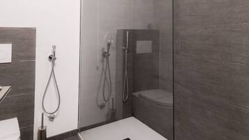 Un baño moderno con ducha de vidrio, lavamanos blanco y retrete.