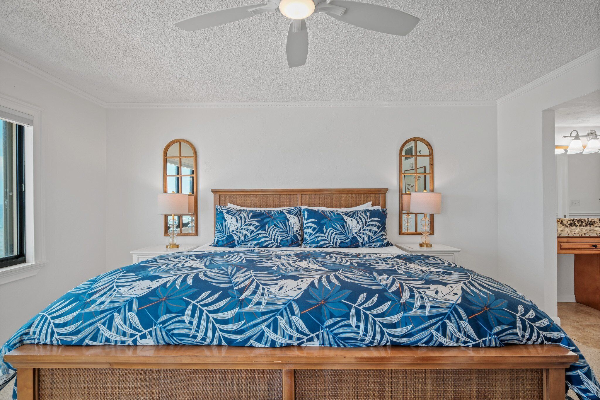A bedroom with a bed, two nightstands, a ceiling fan, and a window.
