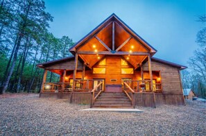Set amidst a forested area, this lodge features a covered porch and a central chimney.