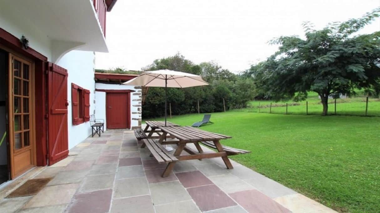 A patio with a picnic table and umbrella, a small seating area, and a well-maintained lawn.