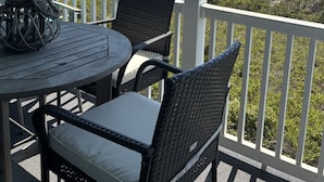 A covered outdoor seating area with a table and chairs, overlooking a beach. - Immaculate 3/2 Oceanfront Condo near Main St, Pool (North Myrtle Beach)