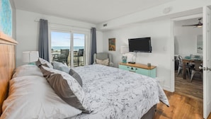A bedroom with a large bed, a television, and a view of the outdoors. - Immaculate 3/2 Oceanfront Condo near Main St, Pool (North Myrtle Beach)