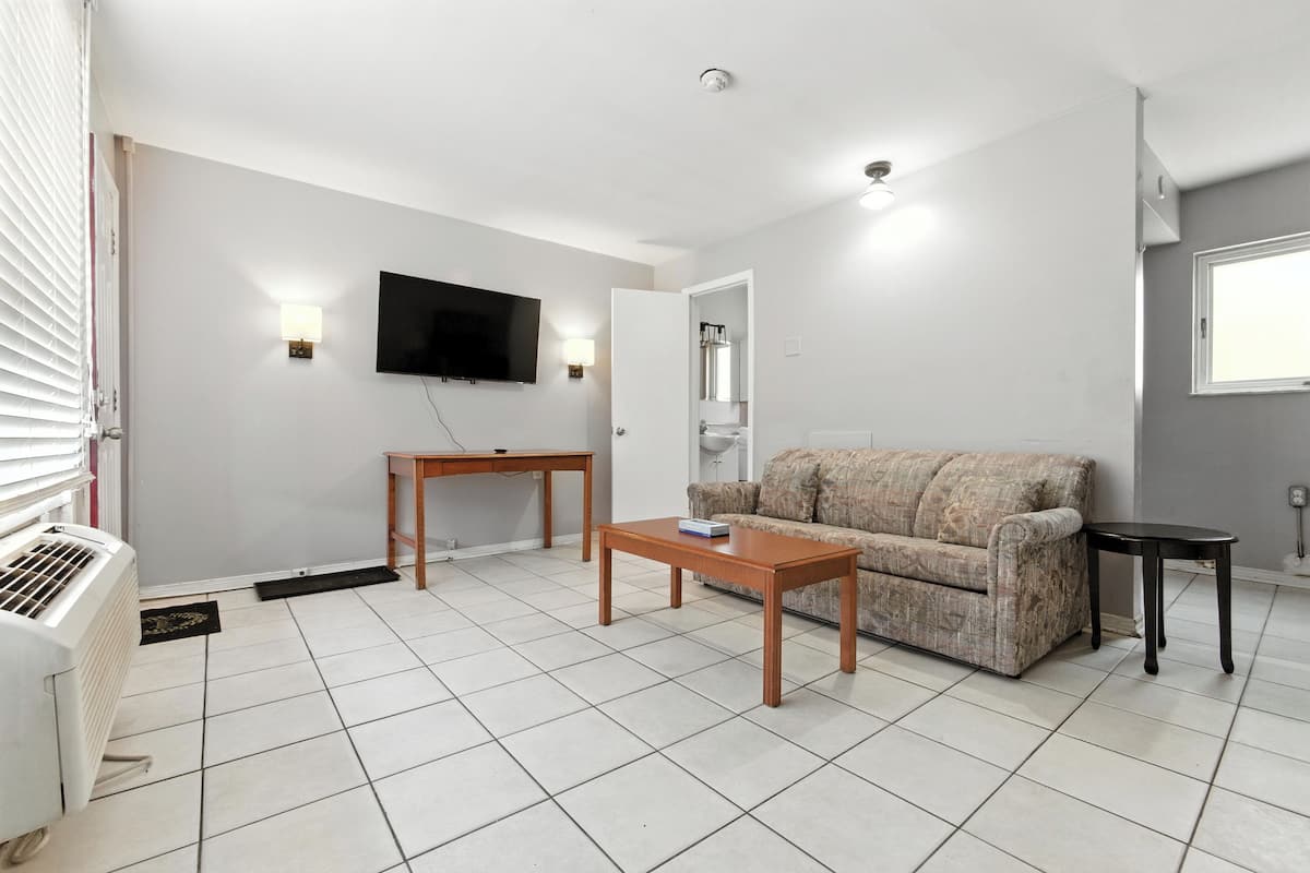 Uma sala de estar com um sofá, uma mesa de centro, uma televisão e uma pequena mesa.