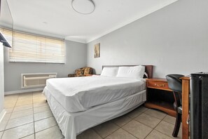 Une chambre à coucher comprenant un lit, une table de chevet, une chaise et un radiateur.
