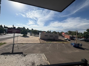 A parking lot with a sign for 'Greeley University Inn' and a small building in the distance. - Greeley University Inn By Capital O I-25 (Greeley)