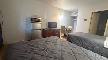 A hotel room with two beds, a television, a desk, and a microwave.