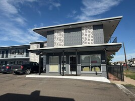 Un edificio moderno con techo plano, ventanas amplias y acceso cubierto.