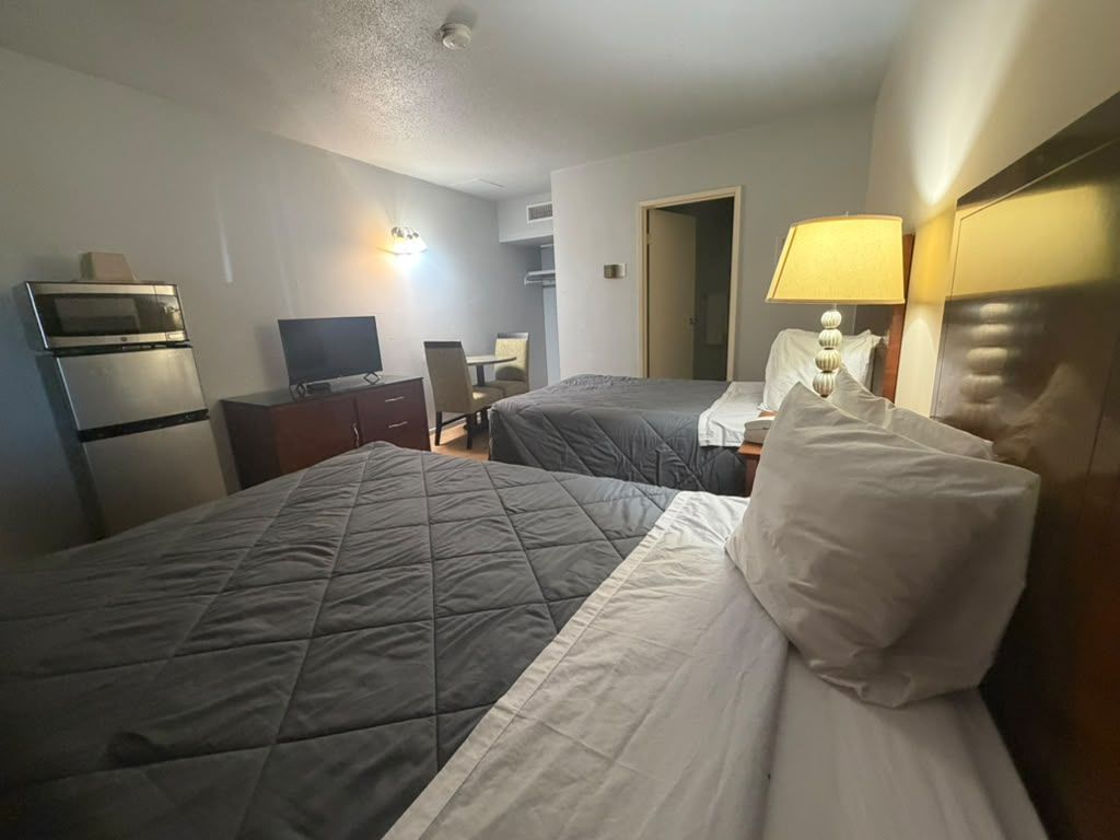 Een hotelkamer met twee bedden, een bureau, een televisie en een magnetron.