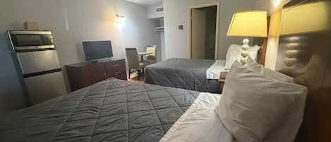 Habitación de hotel con dos camas, un escritorio, televisor y microondas.