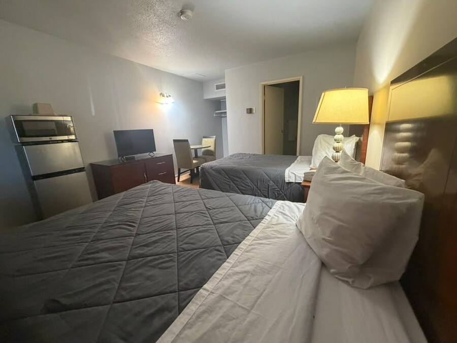 A hotel room with two beds, a desk, a television, and a microwave.