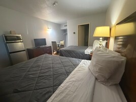 Habitación de hotel con dos camas, un escritorio, televisor y microondas.