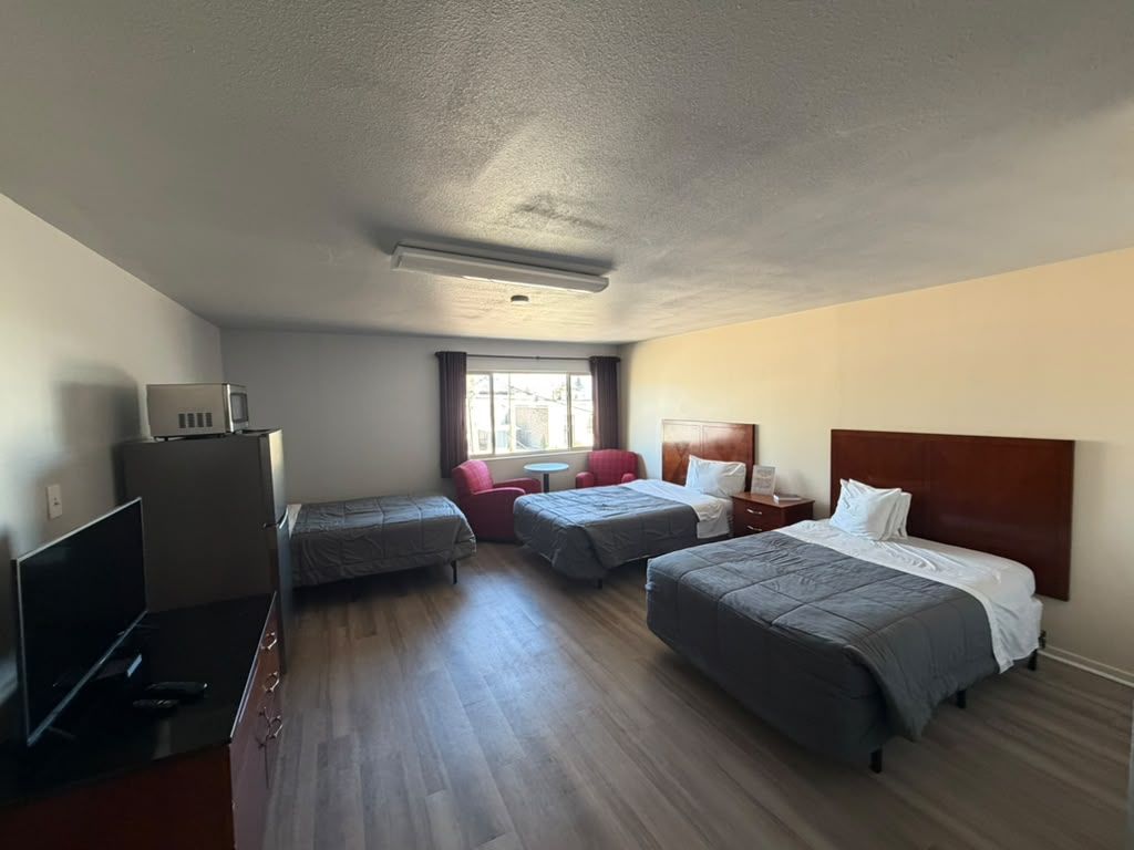 Quarto de hotel com duas camas, televisão, escrivaninha e janela.