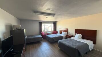 Quarto de hotel com duas camas, televisão, escrivaninha e janela.