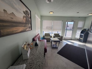 A reception area with a counter, seating, a painting, and a view of the outside.